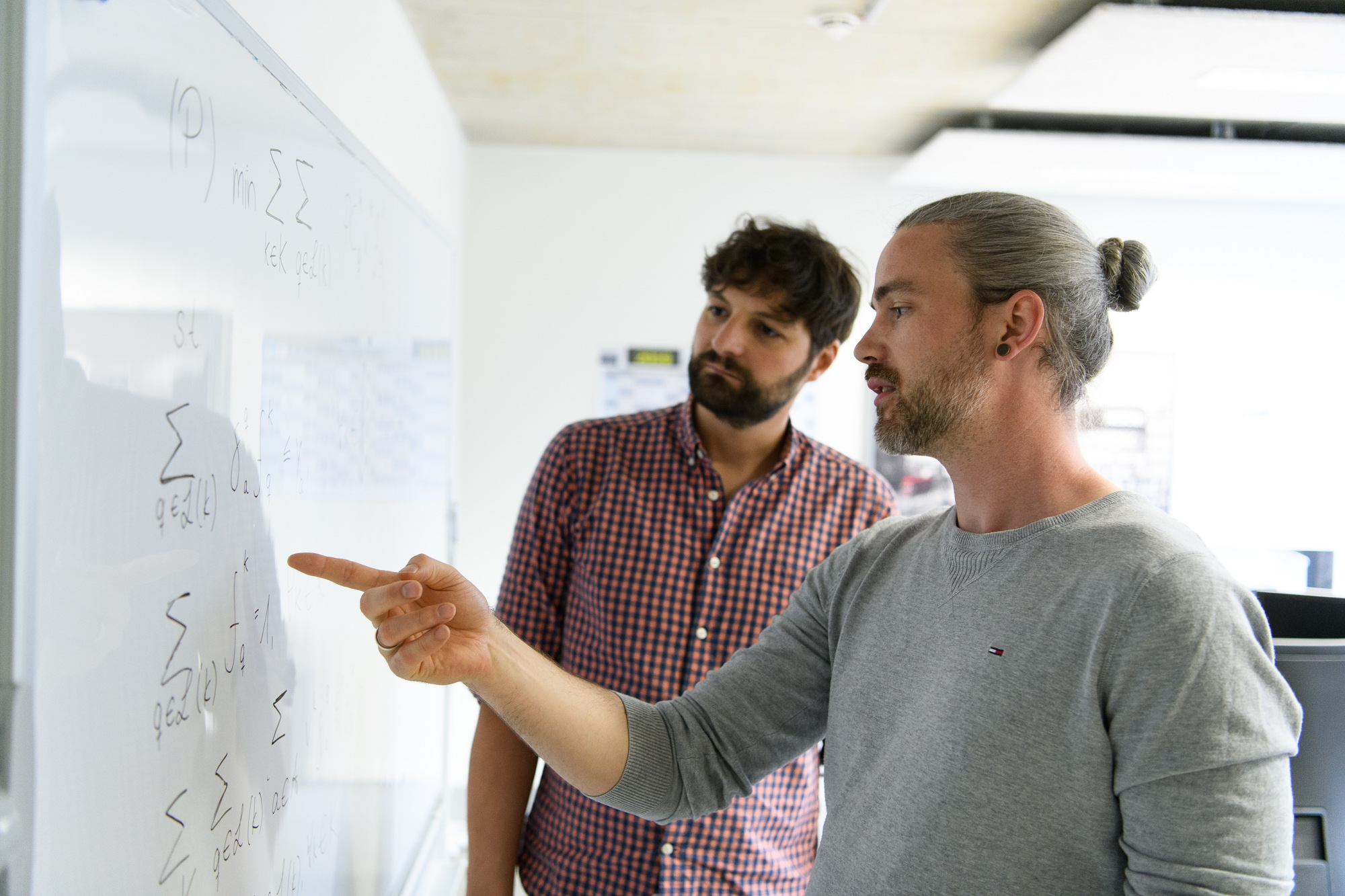 Mathemetische Optimierung - Zwei Data Scientists vor Whiteboard mit mathematischen Formeln